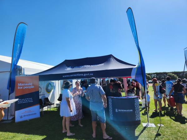 People gather by a Corrections branded marquee at the event